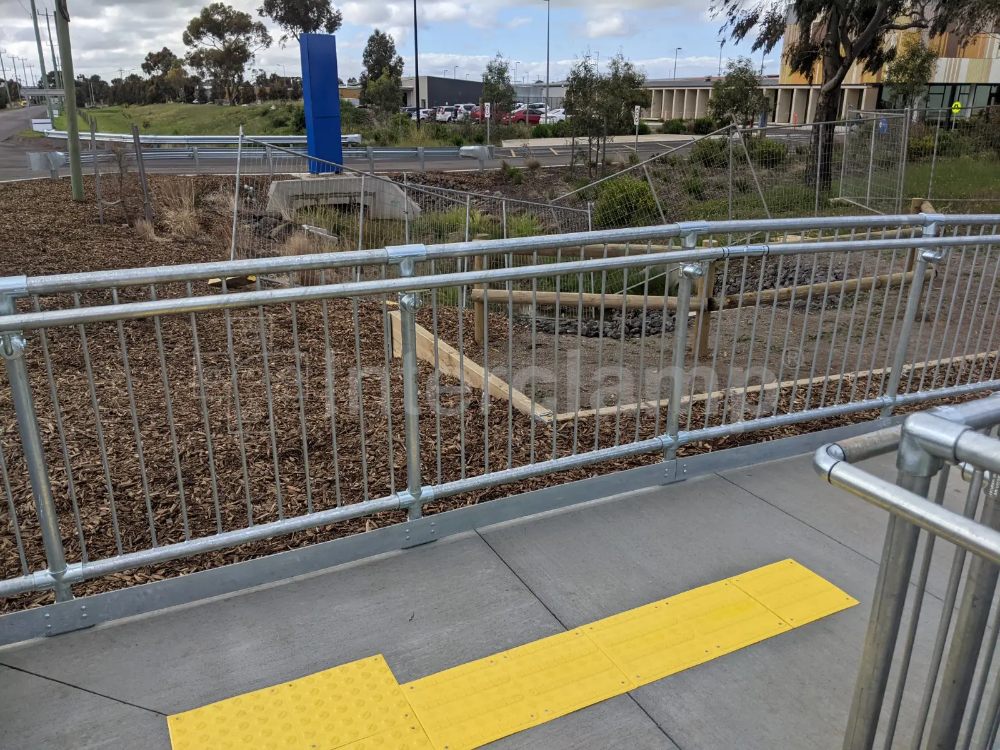 Pedestrian safety barriers made with Interclamp components, including key clamp DDA assist rail, at a bus stop, ensuring secure and orderly boarding for passengers.